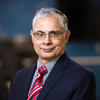A headshot of School of Computing dean Gurdip Singh wearing a navy suit jacket, a light blue shirt and a striped red tie.